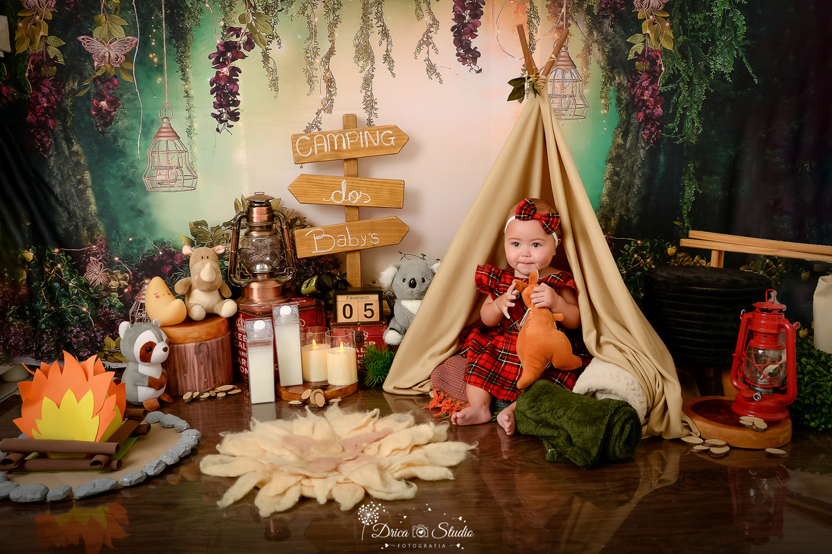 drica studio-ensaio fotografico infantil - acampamento infantil - xinguara - pará -bebê usando vestido xadre vermelho com preto, sentada dentro de cabaninha - lampião - fogueira de eva - plaquinha de indicação - piso amadeirado - tapete felpudo 