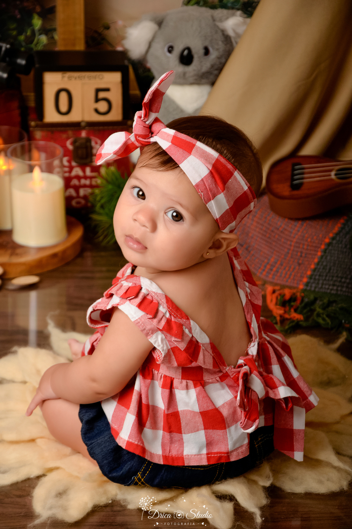 drica studio-ensaio fotografico infantil - acampamento infantil - xinguara - pará -bebê usando blusa xadrez vermelha e branco - violão- vela de led - piso amadeirado - tapete felpudo