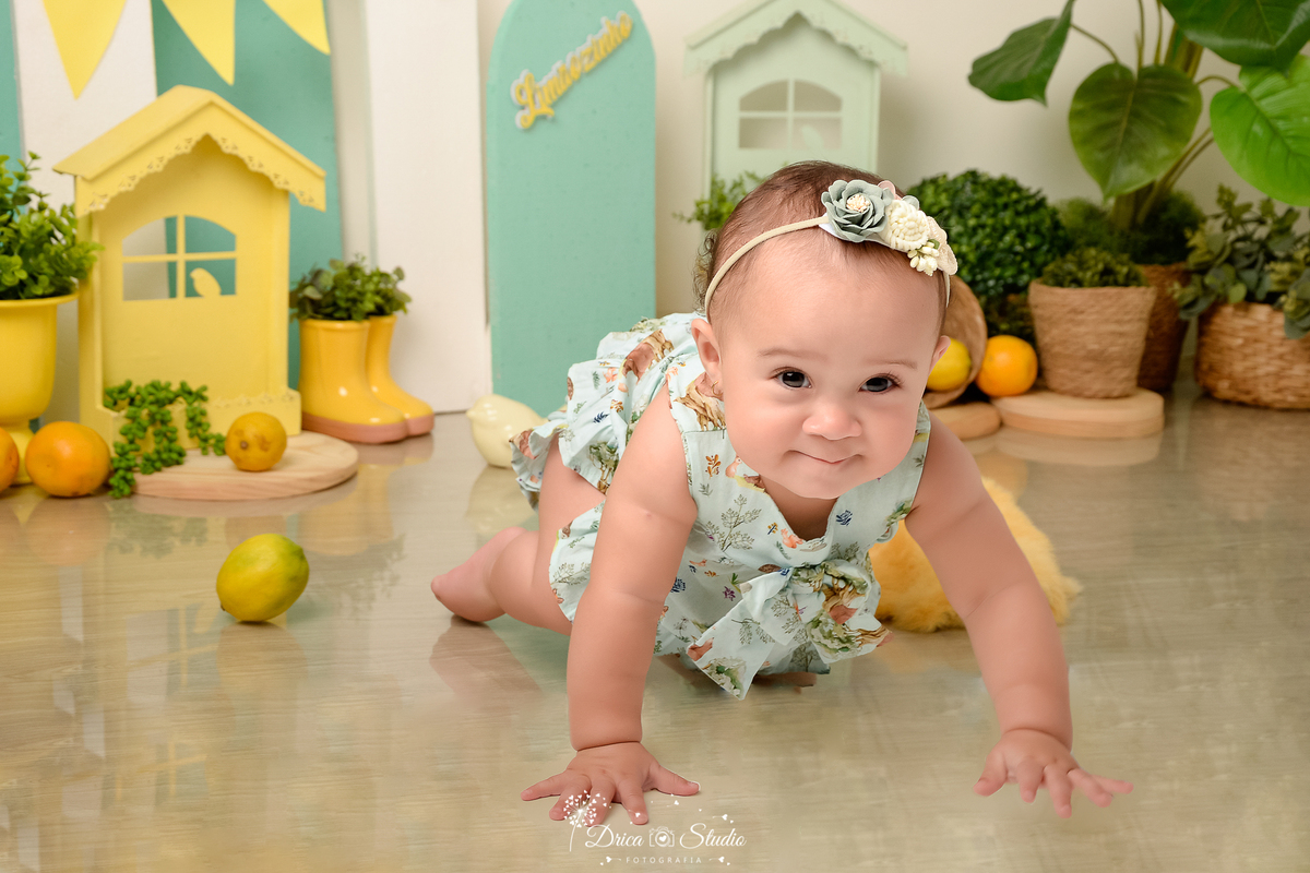 drica studio-ensaio fotográfico infantil - acompanhamento mensal - tema limãozinho - bebê engatinhando- veste bory verde menta com estampa de bichinho - tiara de flores - casinha amarela - cesto de palha - painel verde- botinha amarela - limões