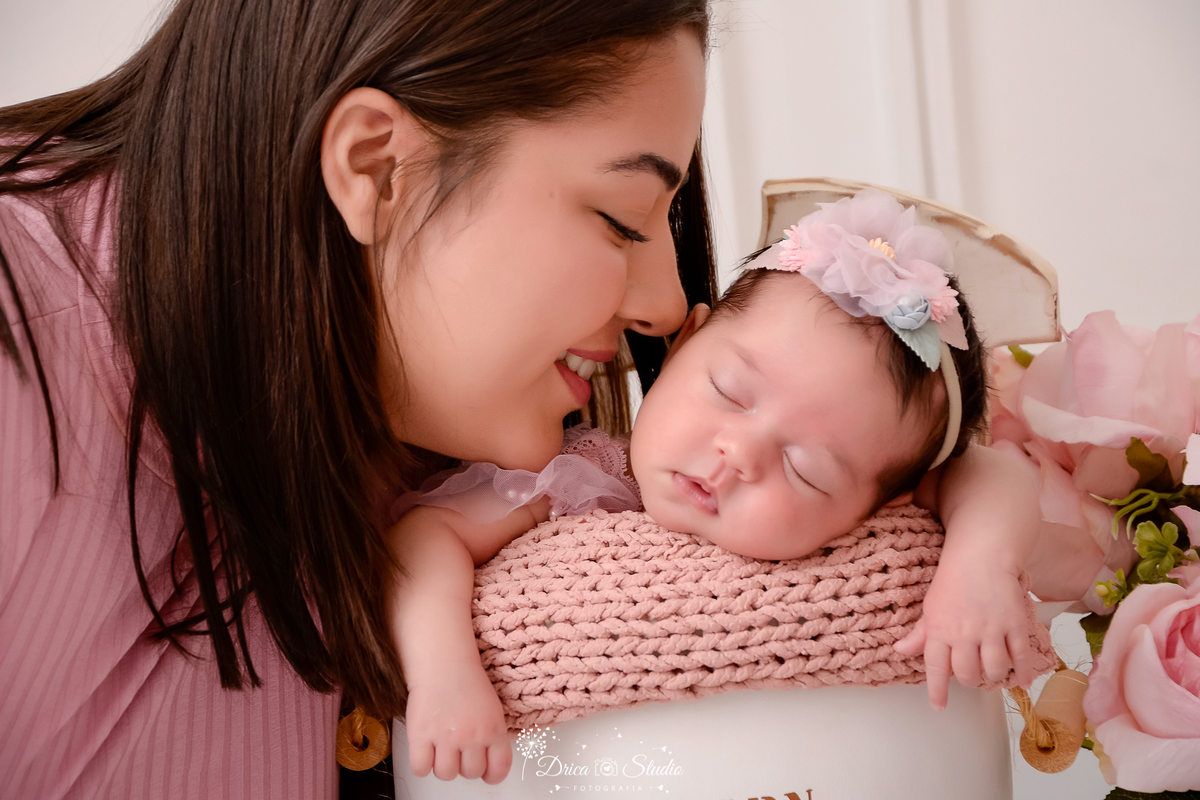 drica studio - ensaio fotografico infantil- recém-nascido- newborn-xinguara-pará-mãe cheirando rostinho de bebê que dorme dentro de cesto acochoado com manta de tricô rose - fundo branco com boiserie e flores rosa