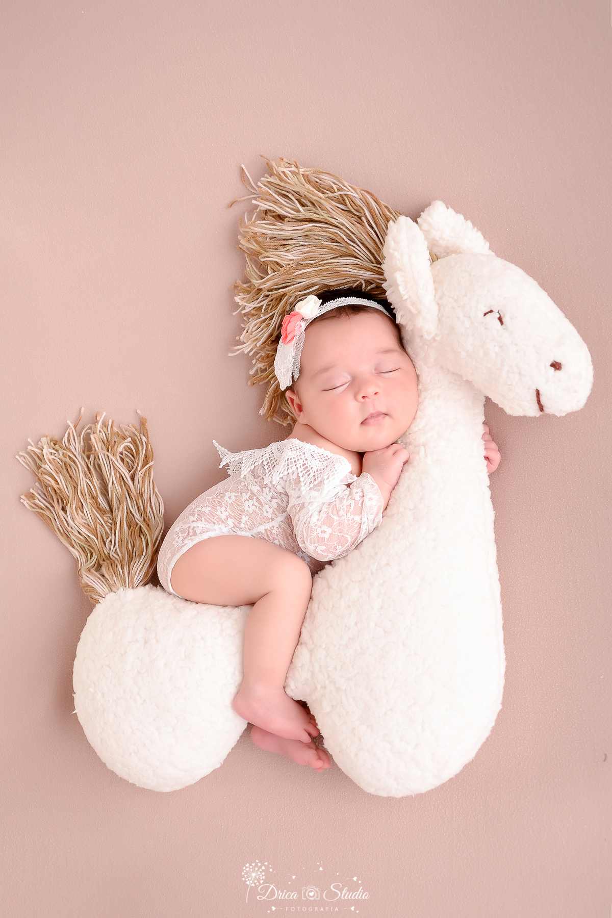 drica studio - ensaio fotografico infantil- recém-nascido- newborn-xinguara-pará-bebê dormindo abraçado com cavalinho de pelucia, vestindo bory branco de renda- fundo neutro