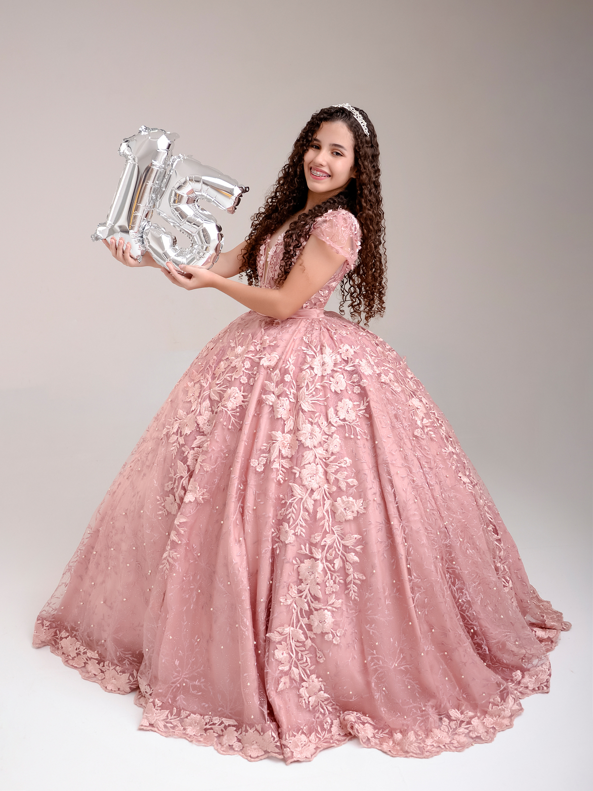 drica studio - ensaio fotografico - debutante 15 anos - aniversário - deburante segurando número 15, ela usa vestido princesa longo rose com renda - fundo neutro