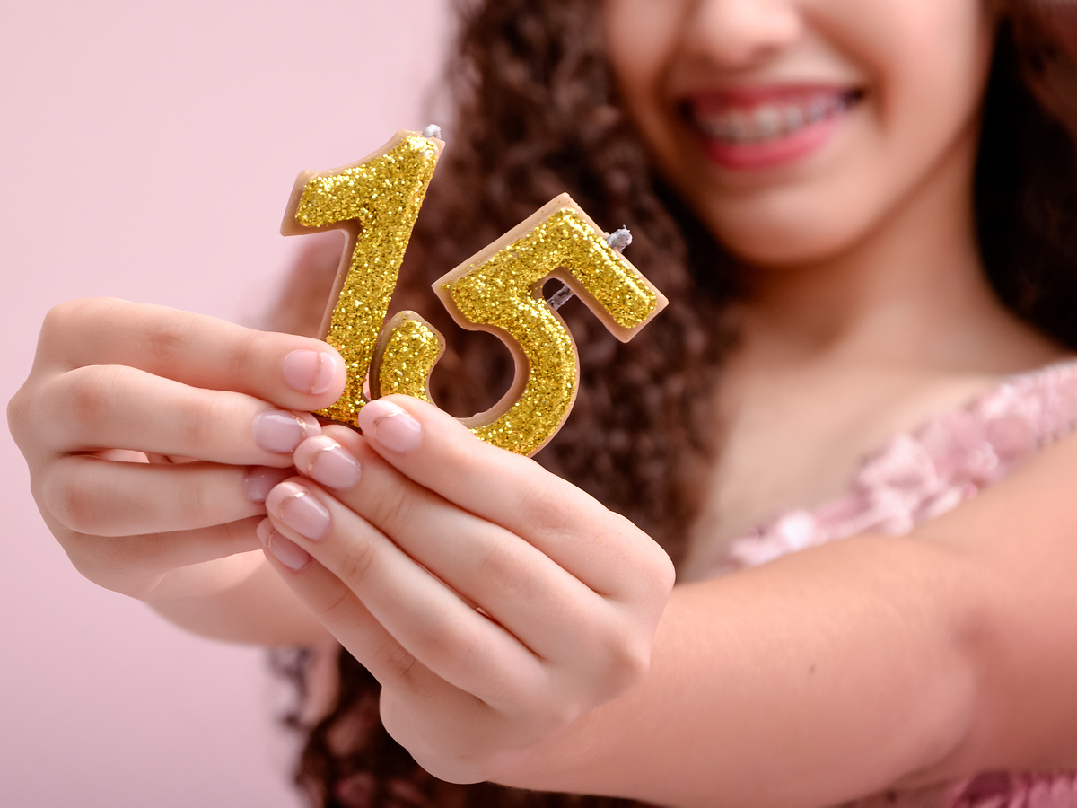 drica studio - ensaio fotografico - debutante 15 anos - aniversário - debutante mostrando vela com número 15 na cor dourada - fundo rose