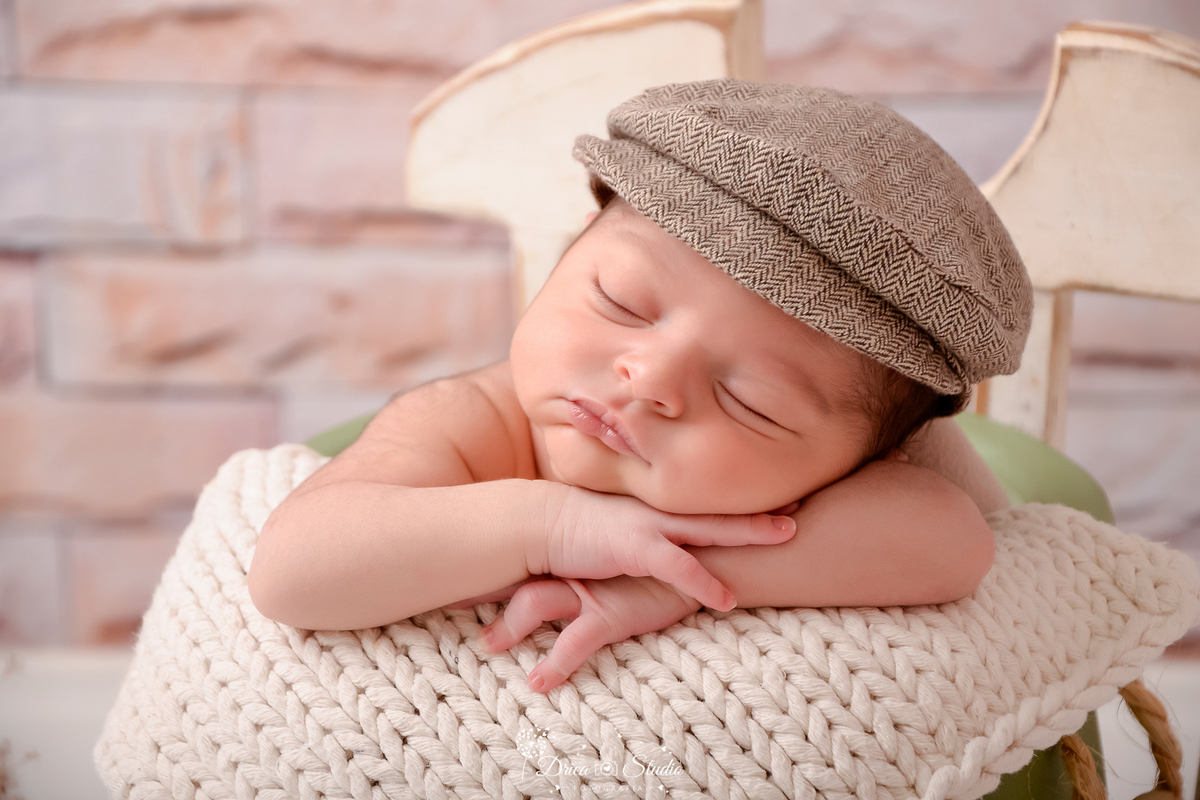 drica studio - ensaio fotografico infantil - recém-nascido - newborn masculino - recêm-nascido dormindo dentro de baldinho verde - boina marrom claro - manta bege de tricô - fundo de tijolinho - cadeira branca 