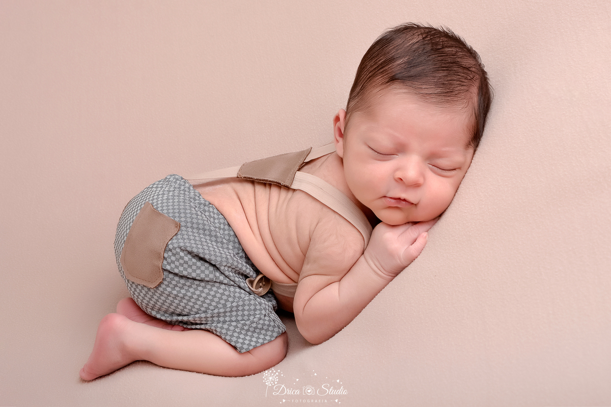 drica studio - ensaio fotografico infantil - recém-nascido - newborn masculino -recém-nascido dormindo em superficie mácia - short cinza com bolso marrom e suspensório bege - 