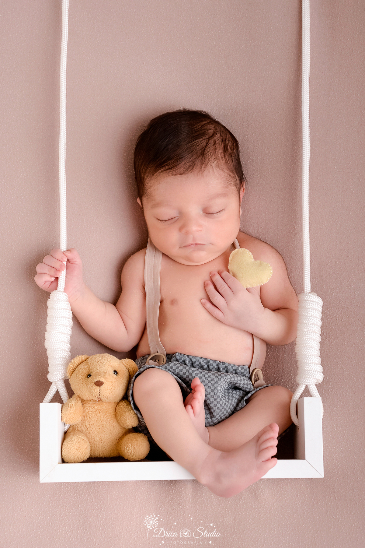 drica studio - ensaio fotografico infantil - recém-nascido - newborn masculino - recém-nascido sentado em balanço branco segurando coraçãozinho de feltro - ursinho de pelúcia amarelo queimado - fundo neutro