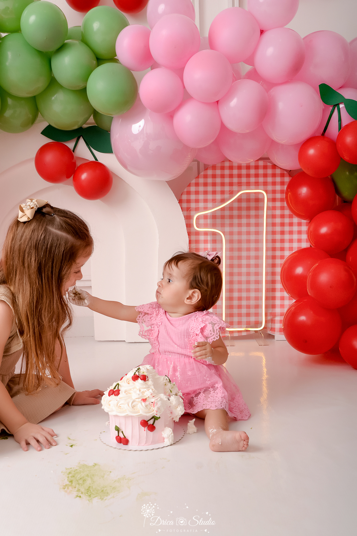 drica studio - ensaio fotografico infantil - smash the cake cerejinha -  irmãs comendo bolo - painel xadrez vermelho com branco - balões vermelho, rosa e verde - arco 3d - cerejinha de balão - 1 de led - vestido rosa com renda - vestido bege