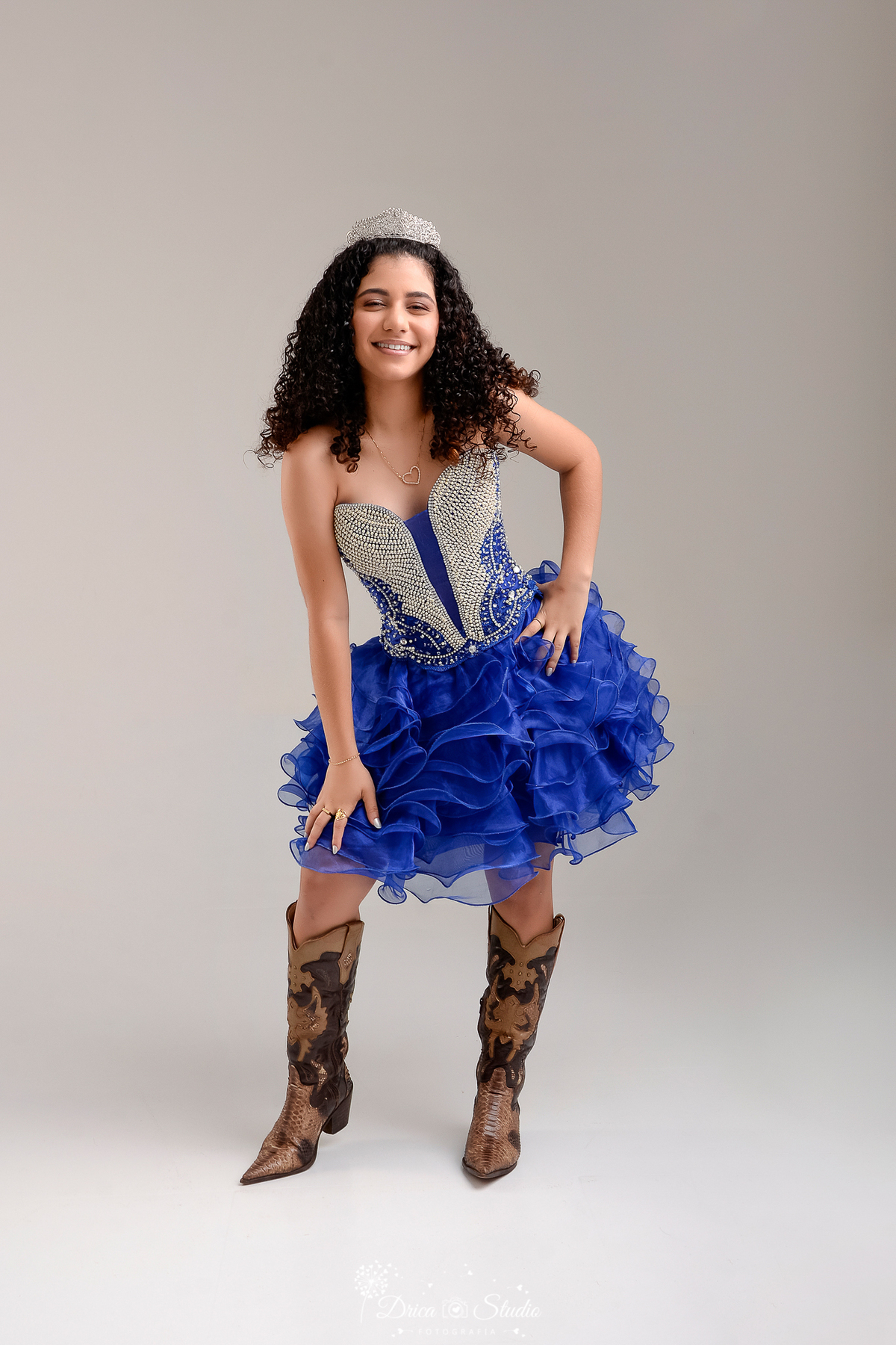 rica studio - ensaio fotografico - 15 anos - debutante - xinguara - pará - jovem com corpo levemente inclinado para frente, usando vestido azul com varias camadas de babado, corpo do vestido com pedrarias - fundo neutro 