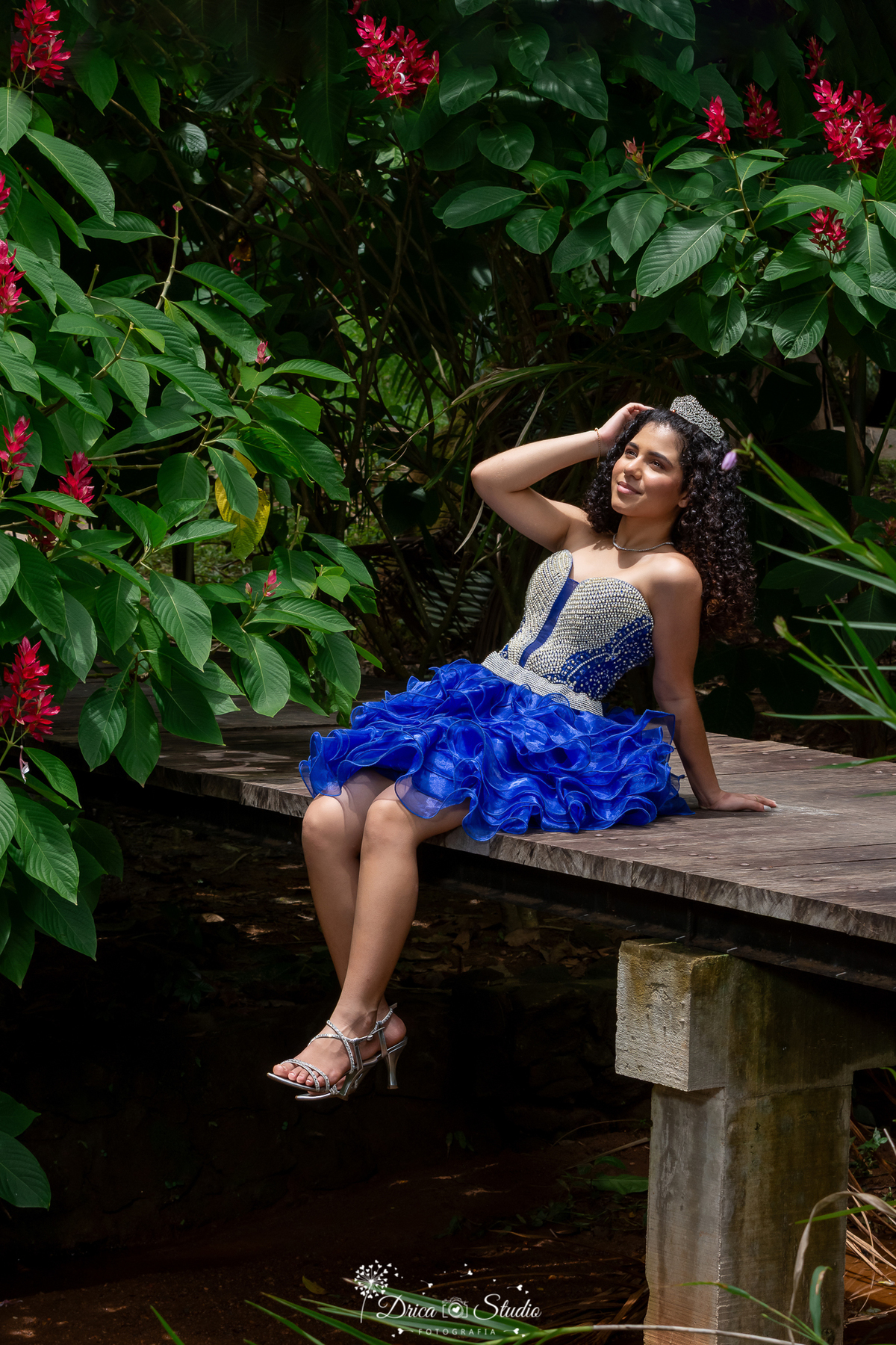 drica studio - ensaio fotografico - 15 anos - debutante - xinguara - pará  - jovem sentada em ponte de madeira em meio ao bosque - vestindo azul com pedraria no corpo e saia com babados - coroa de pedraria - sandália prata