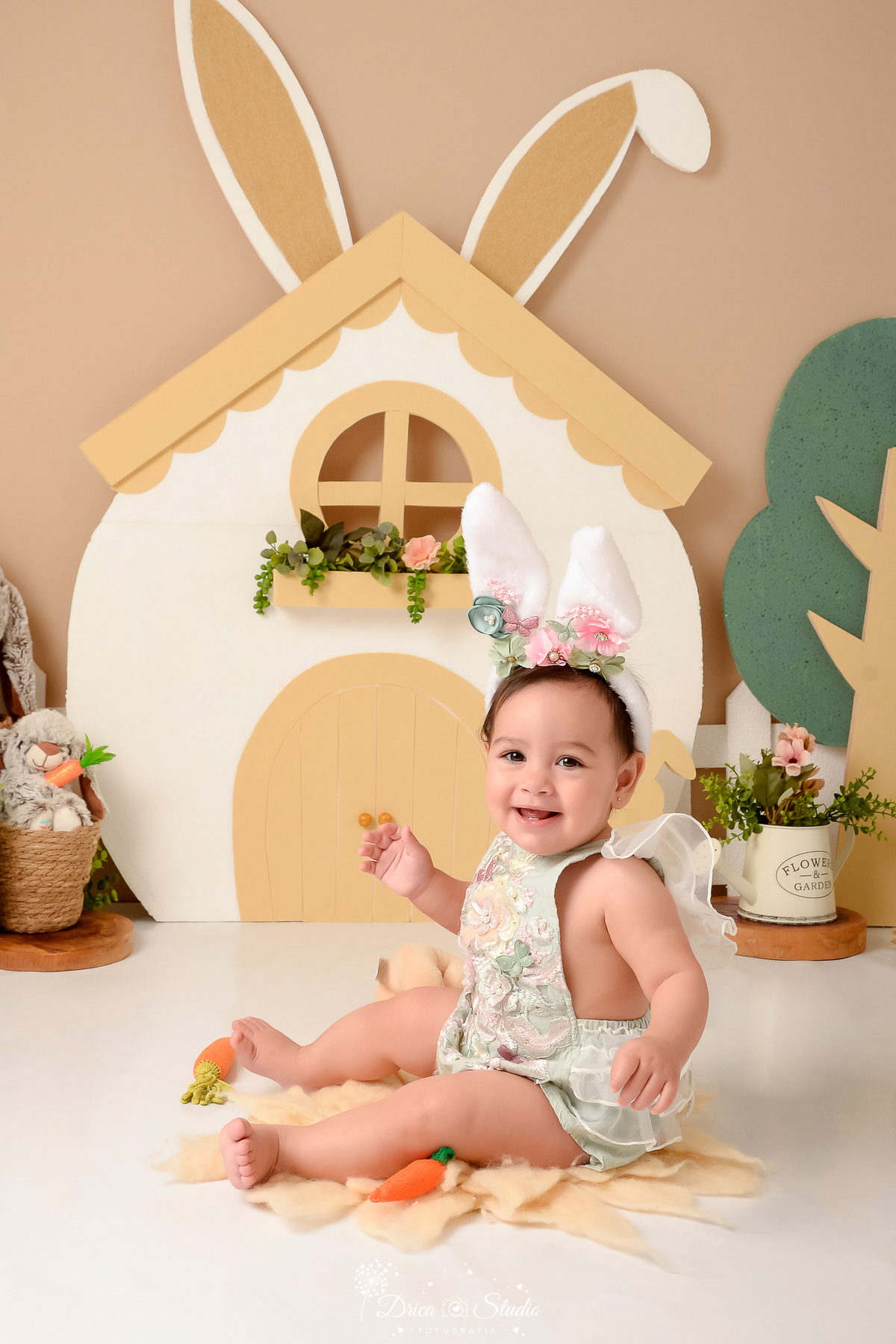 drica studio - ensaio fotografico - acompanhamento mensal - ensaio infantil páscoa - xinguara - pará - bebê usando bory verde agua e tiara com orelhas de coelh - casinha branca - cestos de palha - regador branco com flores - coelho de pelucia-fundo neutro