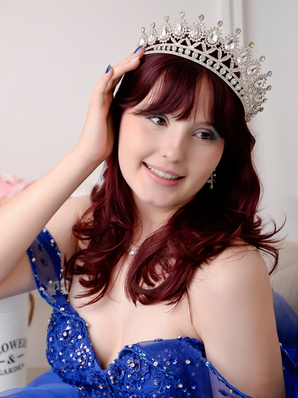 drica studio - fotos 15 anos - aniversario - debutante - estúdio - usando vestido azul com pedrarias -  usando coroa - com a mão no cabelo -