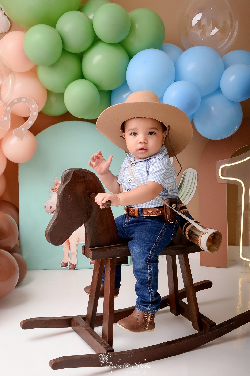 drica studio - ensaio fotografico - fotos em estúdio - xinguara/pá - smash the cake - bebê sentado num cavalinho de madeira - usando camisa xadrez - bota - calça - berrante - e chapeu - cenário country - com balões