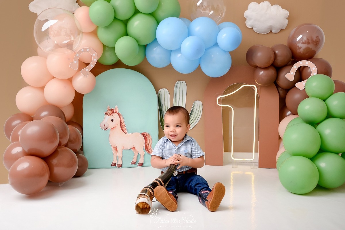 drica studio - ensaio fotografico - fotos em estúdio - xinguara/pá - smash the cake - cenário country - com balões - bebê sentado - usando camisa xadrez - calça - cinto - bota - segurando berrante - bebê sorrindo 