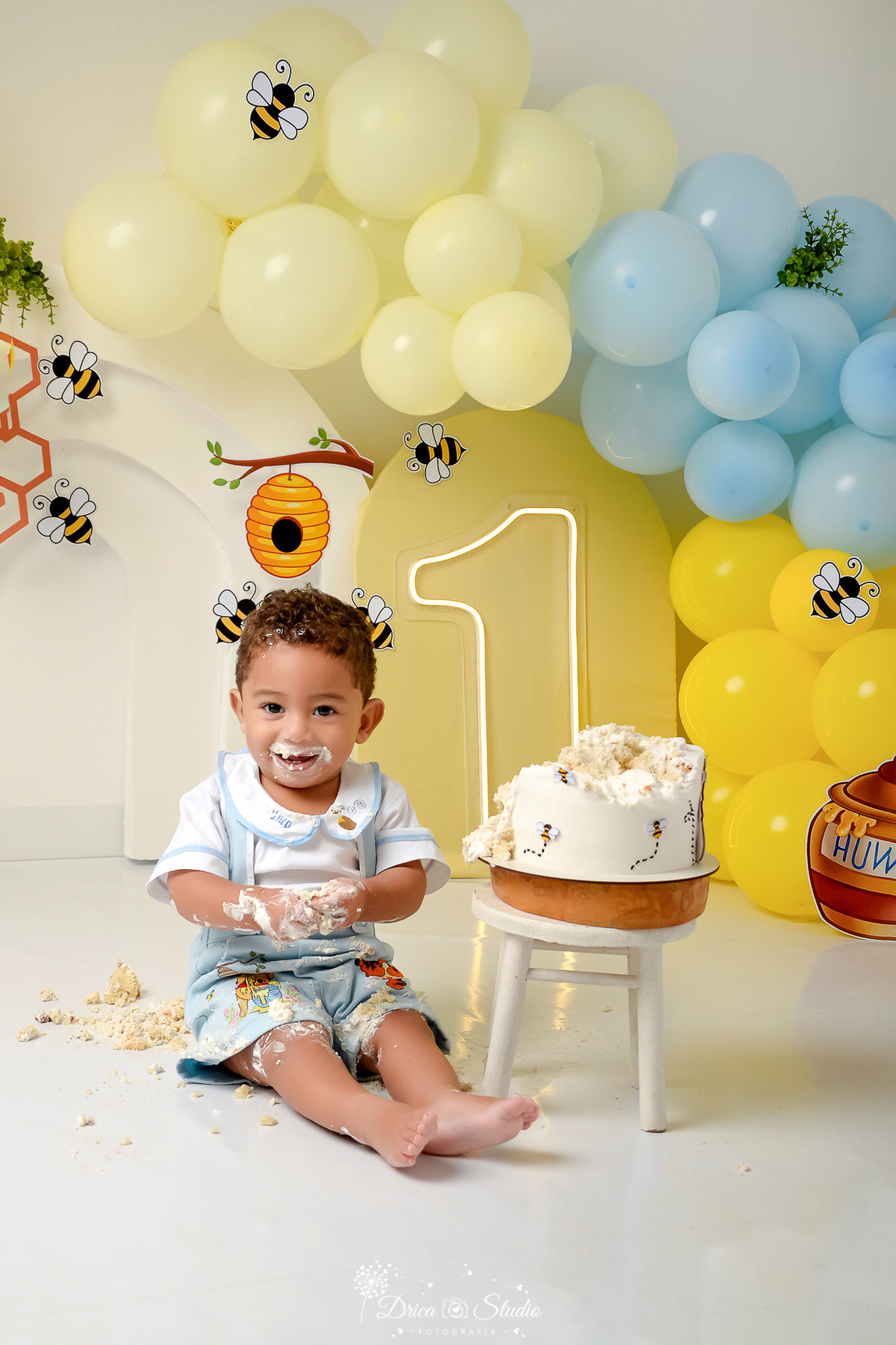drica studio - smash the cake - 1 ano - aniversario - tema ursinho pooh -  cenário com balões - balões azuis e amarelos - abelhas - pote de mel - favo de mel - 1 de led - bolo do ursinho pooh - bebê sorrindo 