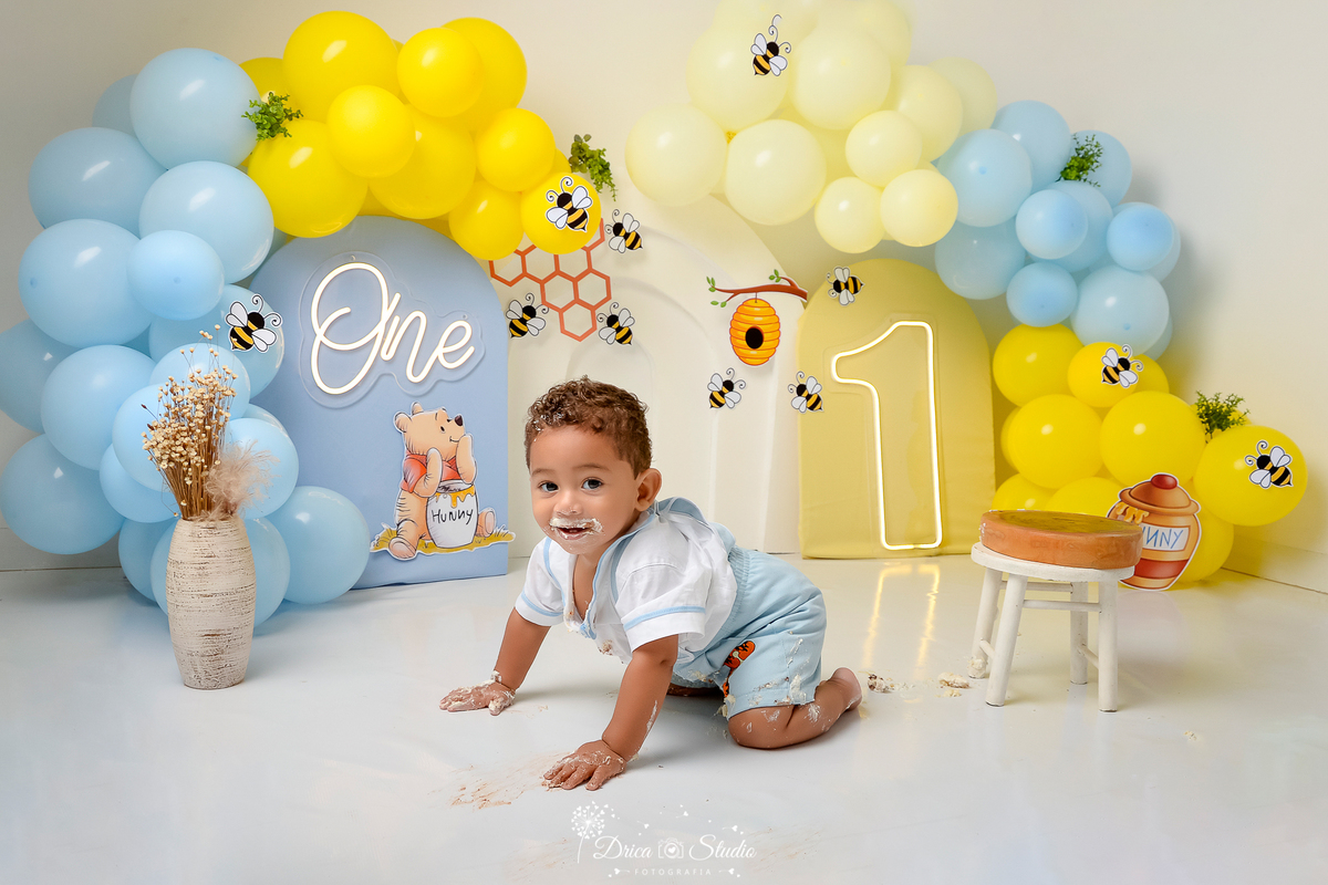 drica studio - smash the cake - 1 ano - aniversario - tema ursinho pooh - cenário com balões - abelhas - favoo de mel - pote de mel - one de led - 1 de led - balões azuis - balões amarelos - bebê engatinhando  