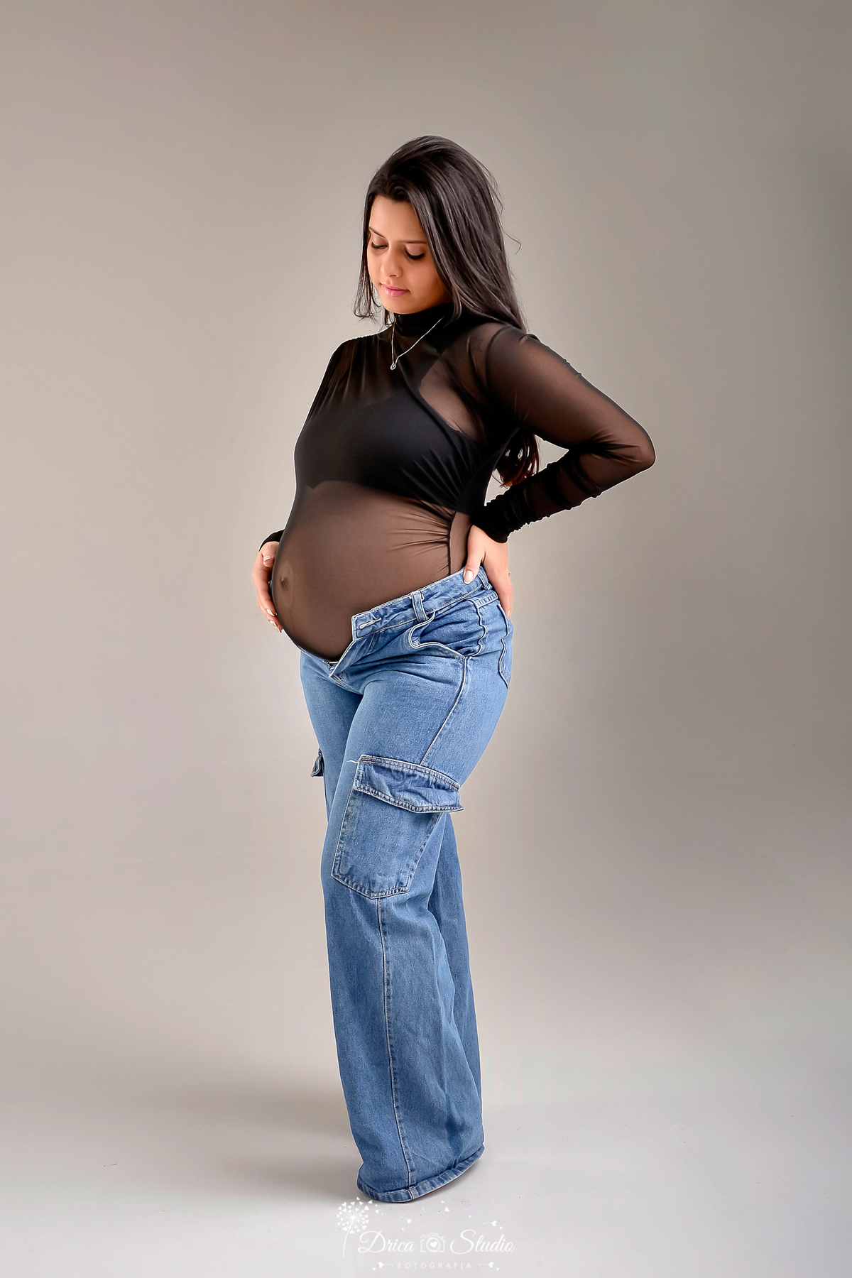 drica studio - xinguara - pará - mamãe de segunda viagem - usando bory preto e calça jeans - foto em fundo branco - mamãe com as mãos na barriga 