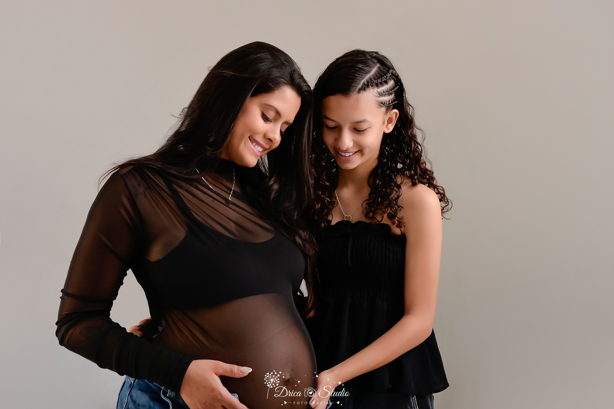 drica studio - xinguara - pará - mãe e filha - usando roupas pretas -  em fundo branco -  olhando para a barriga da mamãe 