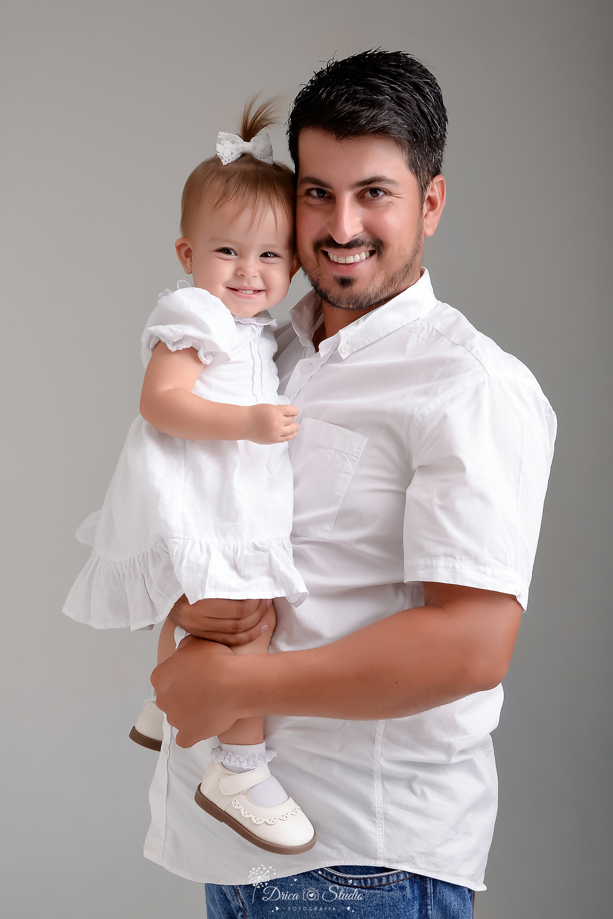 drica studio - fotos familia - xinguara - pará -  pai e filha - foto estudio - fundo branco - papai e bebê usando roupas brancas - pai olhando para a finha - bebê sorrindo 