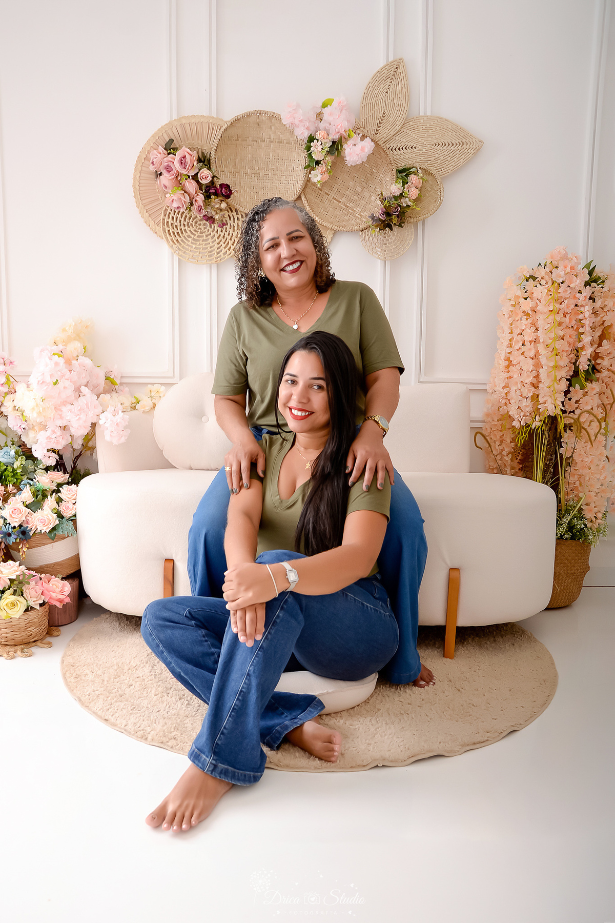 drica studio - ensaio familia - 4 gerações - bizavó - avó - mãe - filha - mãe e filha juntas - mãe sentada no sofá - cenário branco com flores- usando camisas verdes - com calça jeans - escontro de familia 