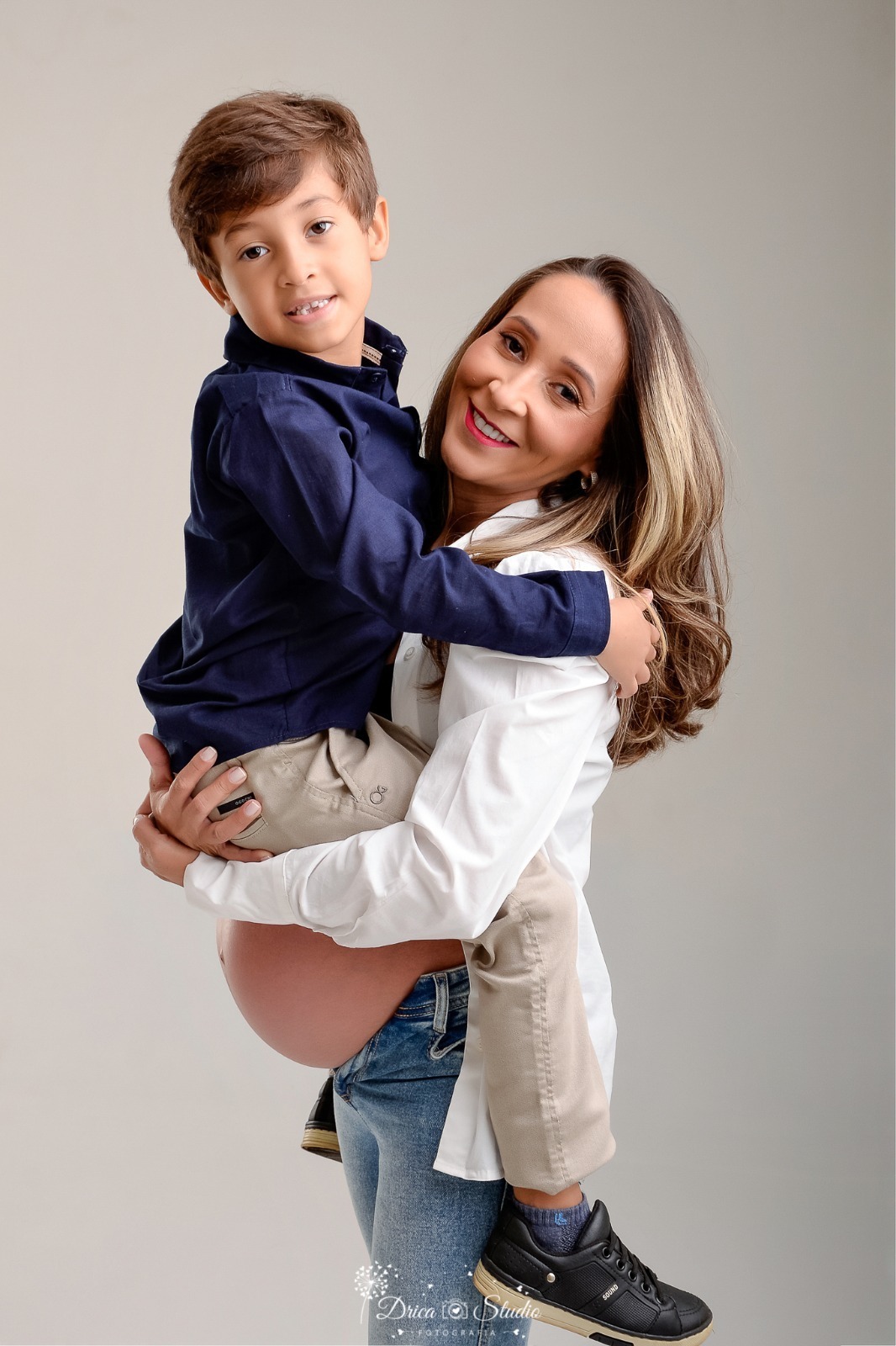 dricastudio - ensaio gestante - mamãe de segunda viagem - mãe de menino - xinguara - pará - mãe segurando o filho mais velha no colo - mãe usando camisa branca - filho usando camisa azul - foto em estudio - fundo branco 