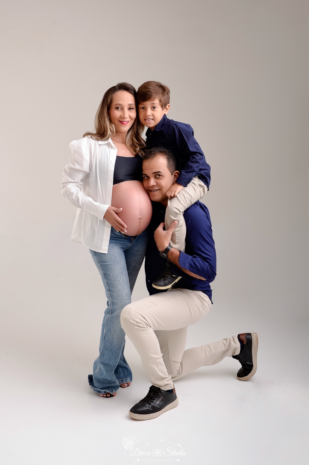 dricastudio - ensaio gestante - mamãe de segunda viagem - mãe de menino - xinguara - pará - familia - mãe usando calça jeans e top preto  com camisa branca - pai e filho usando camisas azuis - foto em estudio - em fundo branco 
