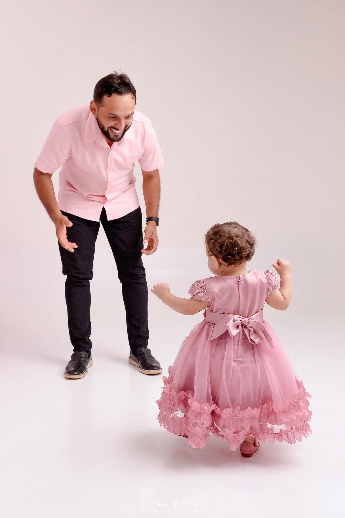 drica studio - smash the cake - jardim encantado - fotos em estudio - bebê dando os primeiros passinhos em direção ao pai - foto em estudio - fundo branco - bebê usando vestido rosa - pai usando camisa rosa 