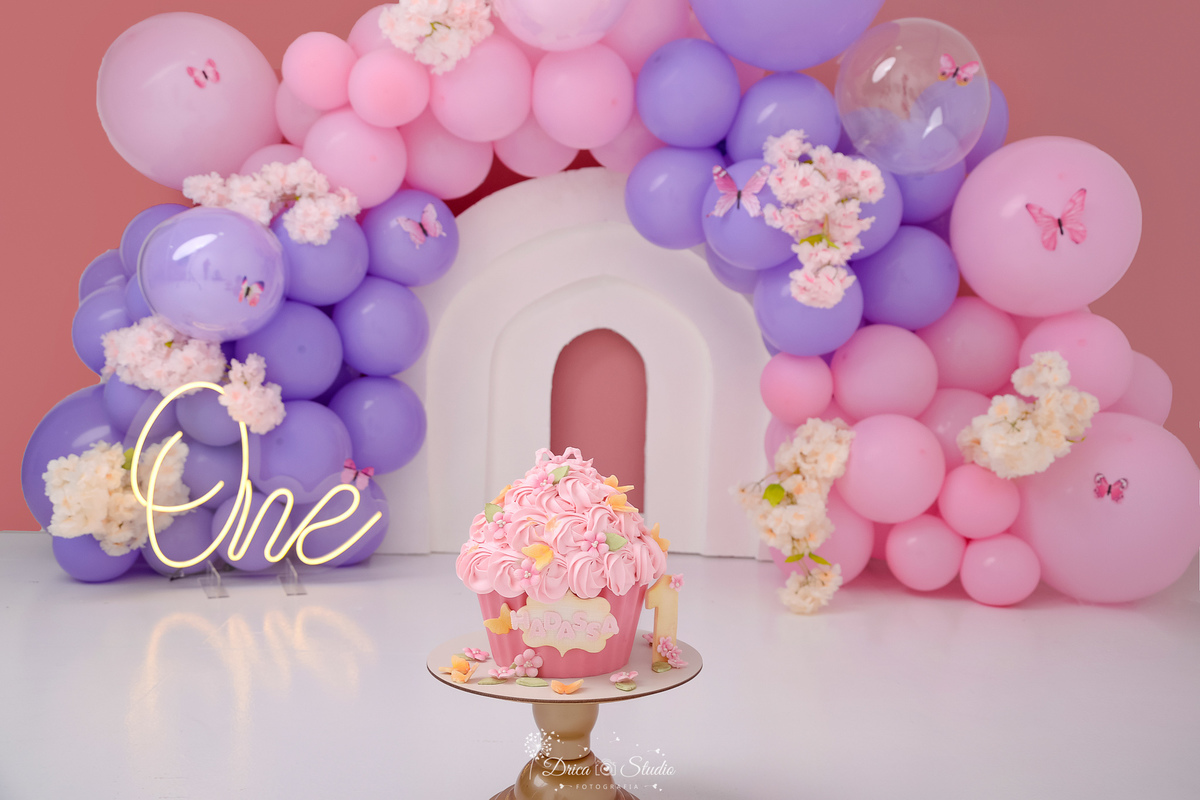 drica studio - smash the cake - jardim encantado - fotos em estudio - cenário com balões rosas e lilás - flores e borboletas - bolo com o nom eda bebê - 