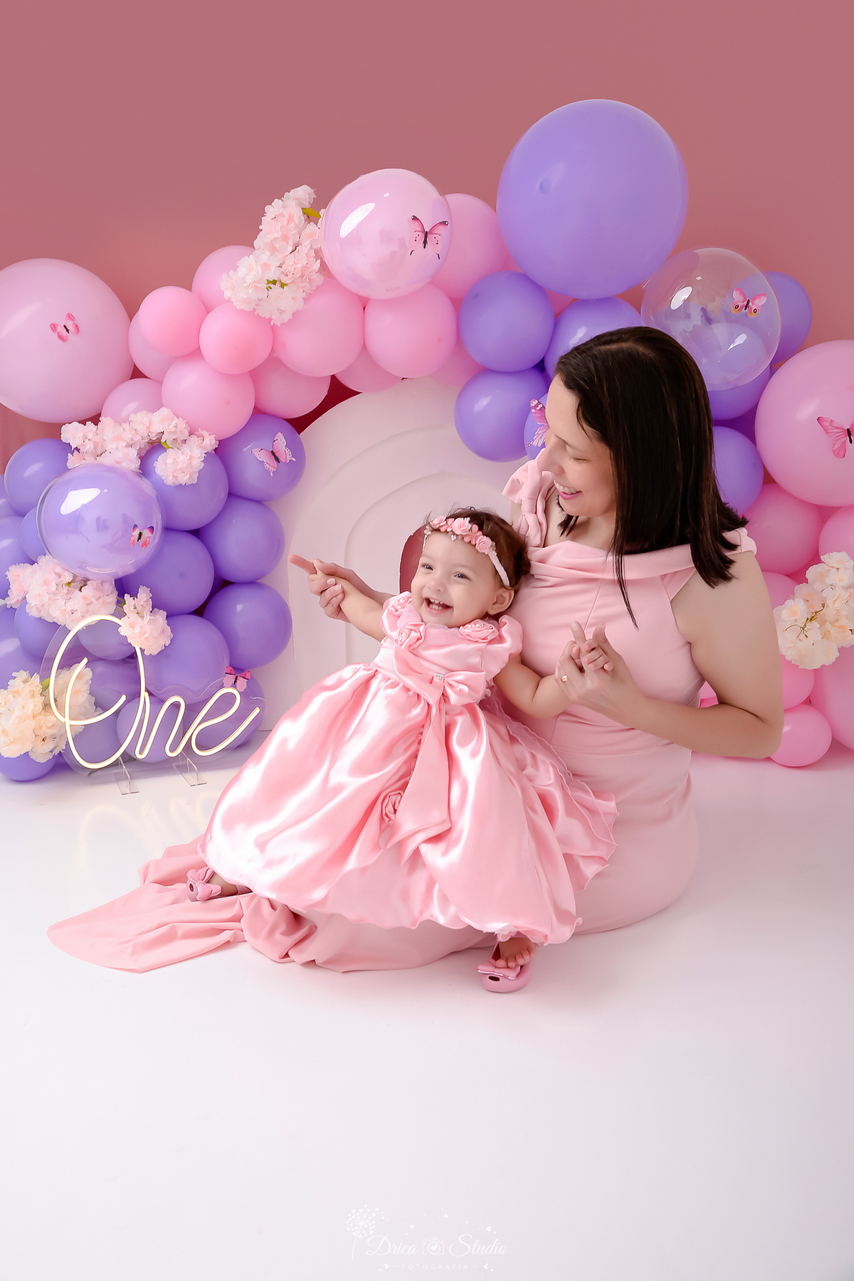 drica studio - smash the cake - jardim encantado - fotos em estudio - cenário com balões rosas e lilás - flores e borboletas - mãe e filha usando vestidos rosas - 