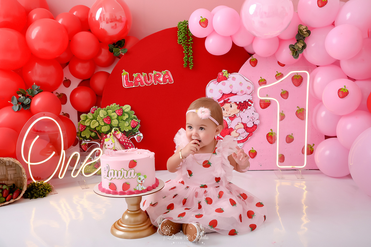 dricastudio - smash the cake - acompanhamento mensal - 1 aninho - xinguara - pará - cenário da moranguinho - cenário com balões rosas e vermelhos - one de led - 1 de led - bebê usando vestido de morangos - bebê comendo um morango 
