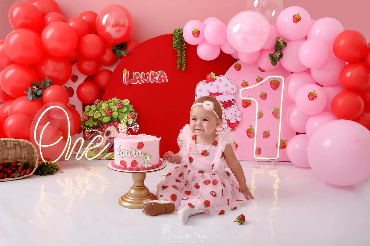 dricastudio - smash the cake - acompanhamento mensal - 1 aninho - xinguara - pará - cenário da moranguinho -  cenário com balões rosas e vermelhos - one de led - 1 de led - bebê usando vestido de moranguinho - bolo da moranguinho 