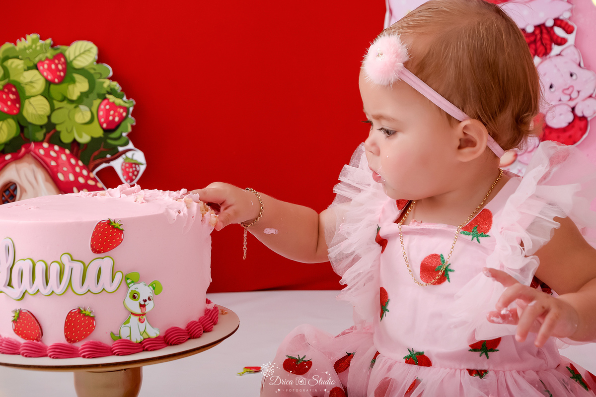 dricastudio - smash the cake - acompanhamento mensal - 1 aninho - xinguara - pará - bebê tocando no bolo - usando vestido de moranguinho e laço - 