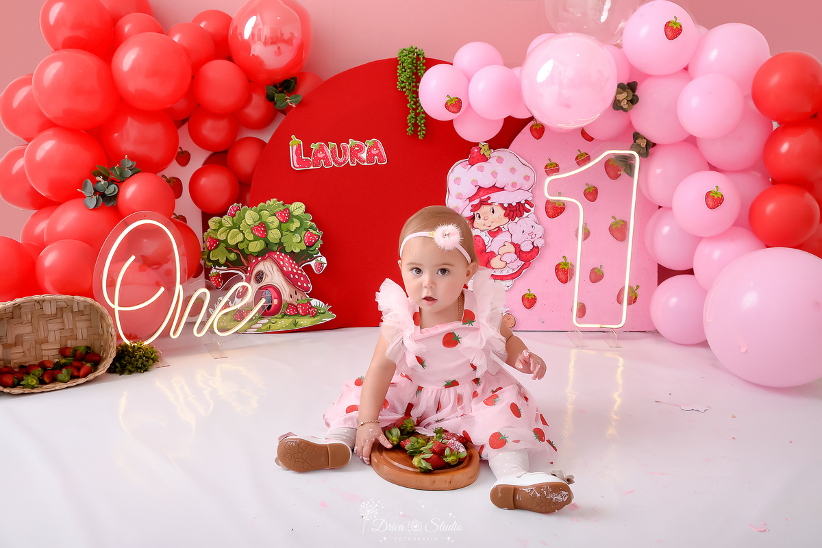 dricastudio - smash the cake - acompanhamento mensal - 1 aninho - xinguara - pará - cenário d amoranguinho -  cenário com balões rosas e vermelhos - bandeja de morangos - one de led - 1 de led - bebê usando vestido de morangos 