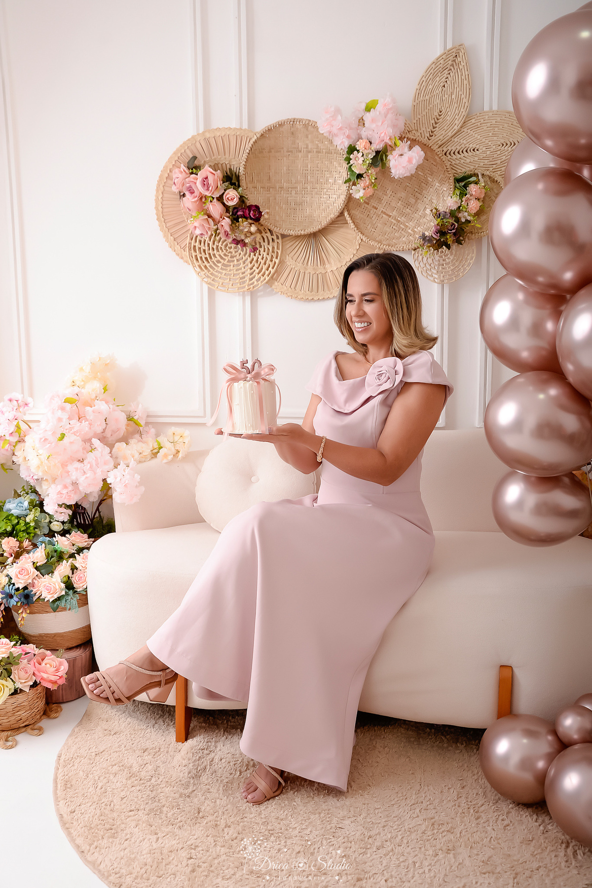 Ensaio comemorativo de 50 anos realizado em estúdio com iluminação suave e elegante.
Cliente vestindo um sofisticado vestido em tom rosa claro, transmitindo delicadeza e feminilidade.
Sorriso espontâneo e acolhedor, 