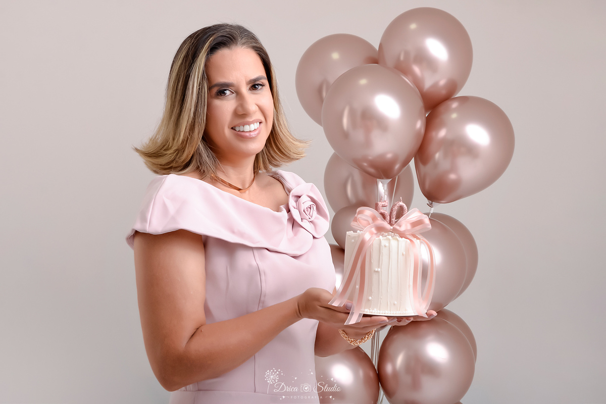 Ensaio comemorativo de 50 anos realizado em estúdio com iluminação suave e elegante.
Cliente vestindo um sofisticado vestido em tom rosa claro, transmitindo delicadeza e feminilidade.
Sorriso espontâneo e acolhedor