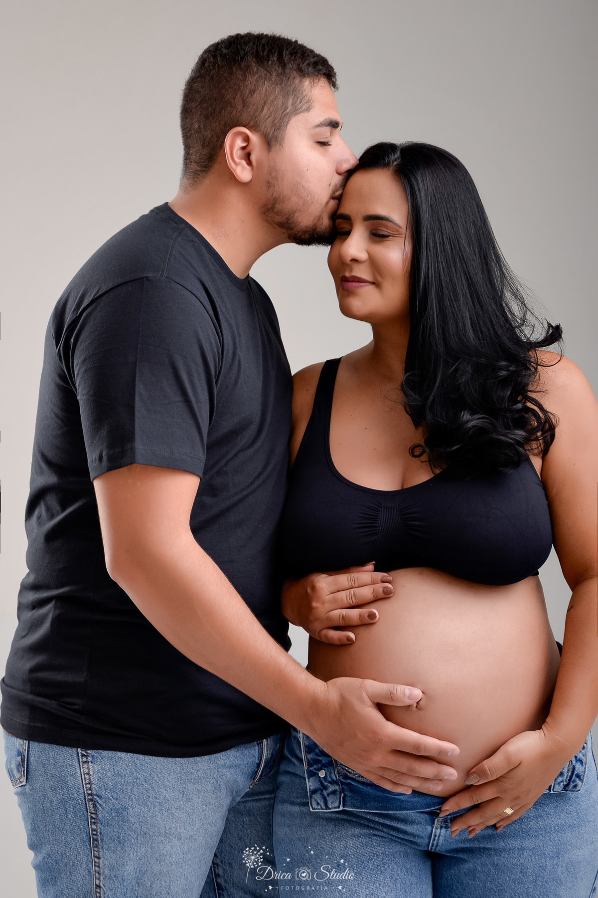 EnsaioGestante - MeninaACaminho - ÀEsperaDaPrincesa - PrimeiraFilha - FotografiaGestante Família - Gestação - MemóriasParaSempre - drica studio - fotos em studio - gestante usando calça jeans e tope preto -  esposo usando camisa preta e calça jeans 