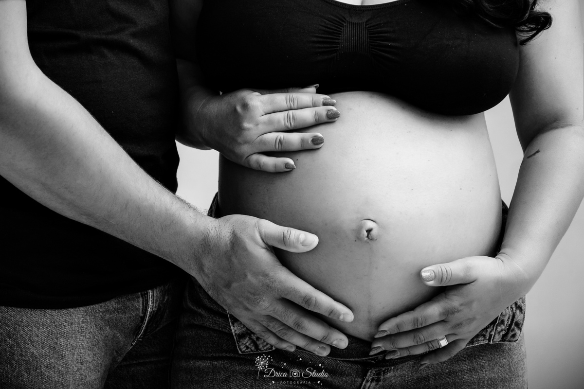 EnsaioGestante - MeninaACaminho - ÀEsperaDaPrincesa - PrimeiraFilha - FotografiaGestante Família - Gestação - MemóriasParaSempre - drica studio - fotos em studio - gestante usando calça jeans e tope preto -esposo usando camisa preta e calça jeans 