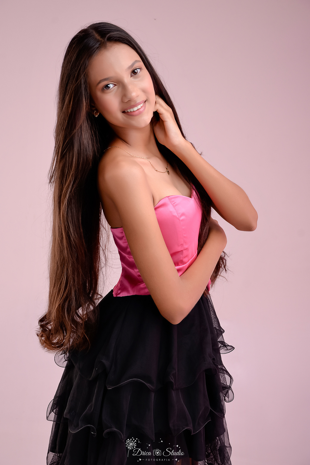 15 anos - ensaio debutante - drica studio - xinguara - pará - fotos em estudio - usando vestido rosa e preto - luz de fundo rosa - com a mão no rosto 