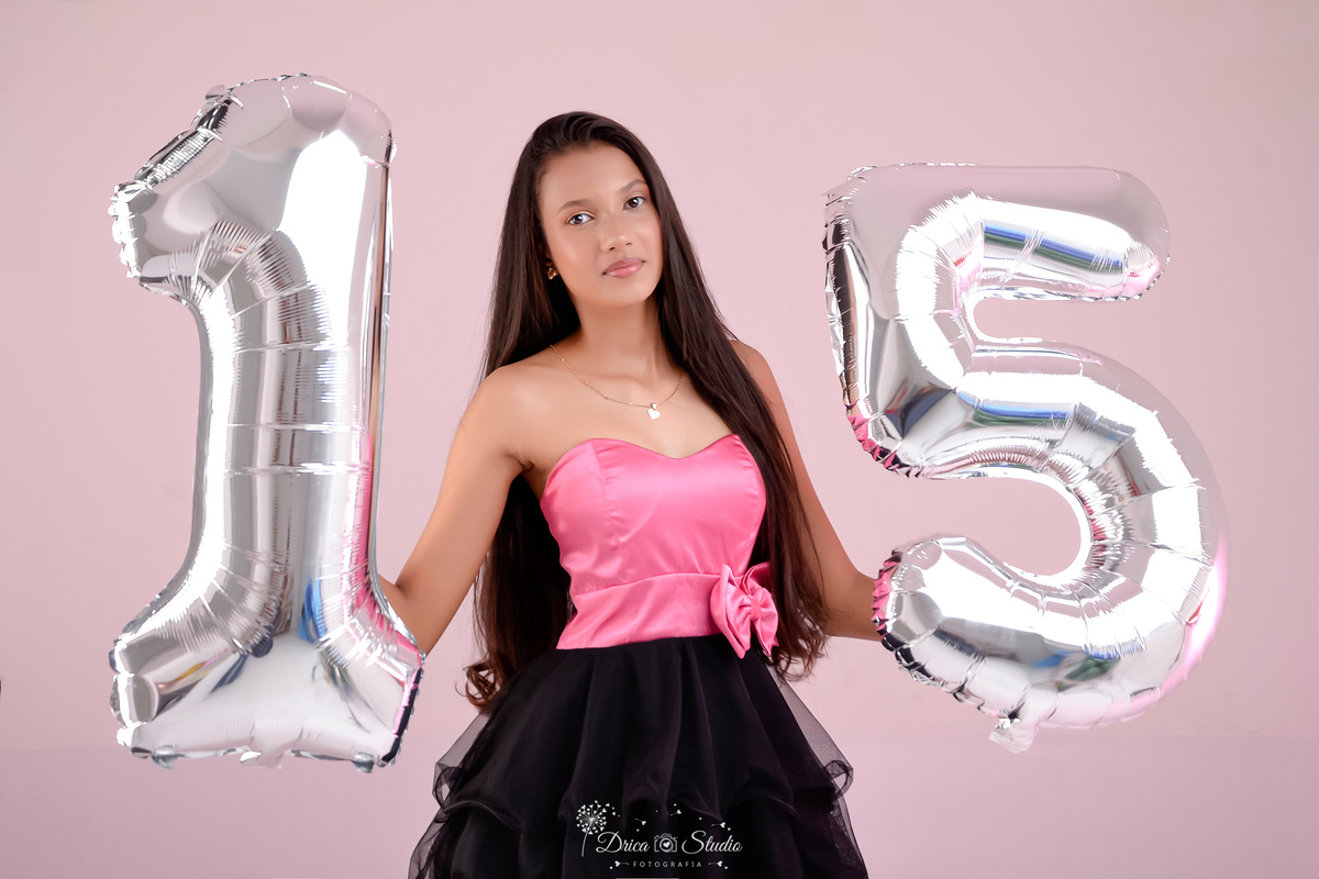 15 anos - ensaio debutante - drica studio - xinguara - pará - fotos em estudio - usando vestido rosa e preto  -  com balões de numero 15 -  luz de fundo rosa 