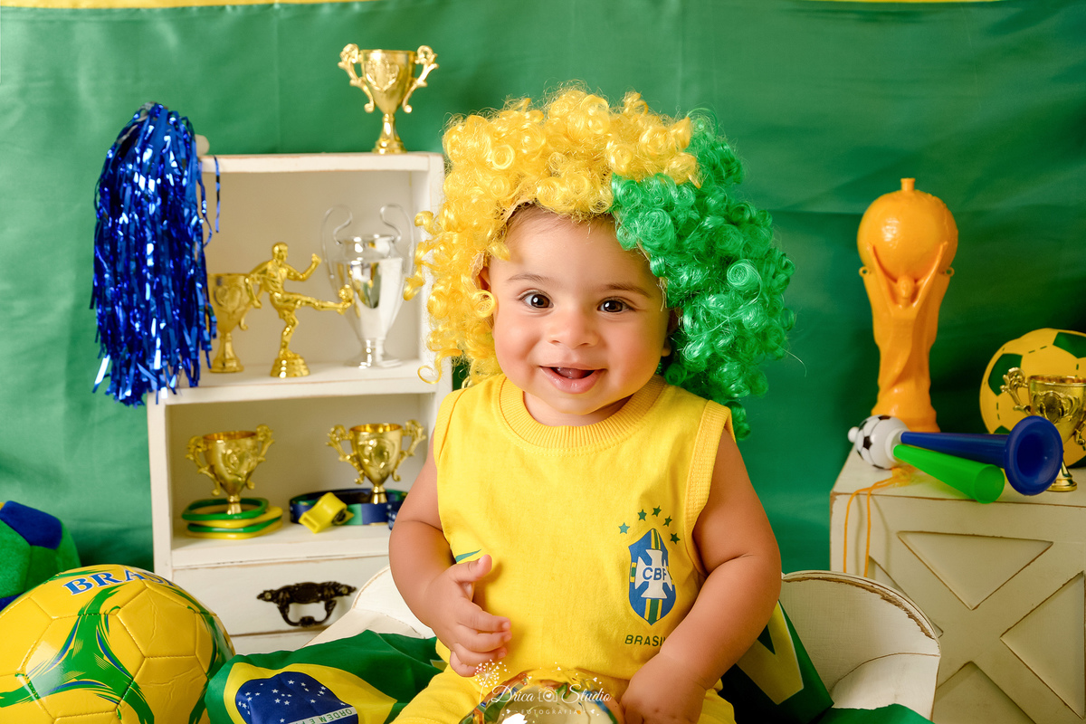 Drica Studio - Copa2026 -Lembrança especial primeira copa - cenário de copa - verde, amarelo e azul -  bebê usando bory amarelo do brasil - com peruca verde e amarelo - cenários com taças da copa - bolas de futbol 