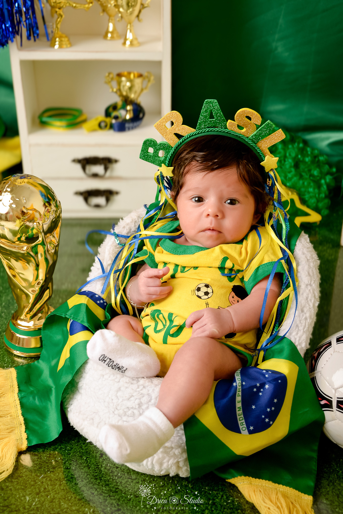 Drica Studio - Copa2026 -Lembrança especial primeira copa - cenário de copa - verde, amarelo e azul - bebê usando bory amarelo do brasil - com tiara do brasil - com a taça da copa ao lado 