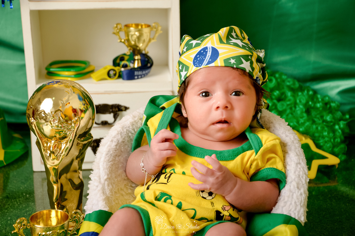 Drica Studio - Copa2026 -Lembrança especial primeira copa - cenário de copa - verde, amarelo e azul - bebê com bory amarelo do brasil - com bandana do brasil na cabeça - sentada em uma cadeirinha branca - ao lado da taça da copa 