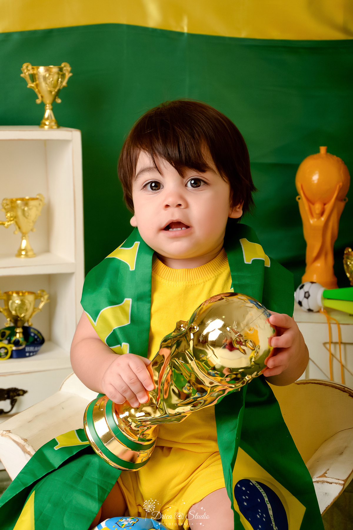 Drica Studio - Copa2026 -Lembrança especial primeira copa - cenário de copa - verde, amarelo e azul - bebê segurando a taça de copa - usando bandeira do brasil 