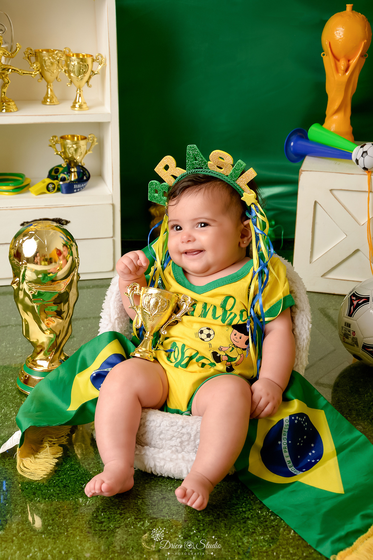 Drica Studio - Copa2026 -Lembrança especial primeira copa - cenário de copa - verde, amarelo e azul -  bebê usando bory amarelo do brasil - usando tiara do brasil - com a taça da copa ao lado 