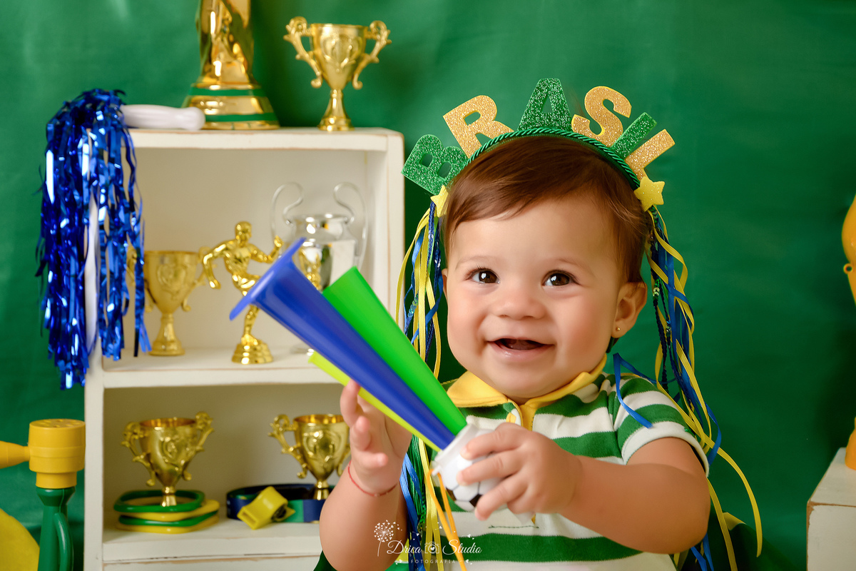 Drica Studio - Copa2026 -Lembrança especial primeira copa - cenário de copa - verde, amarelo e azul - bebê usando bory do brasil - com tiara do brasil - com buzina verde e azul 