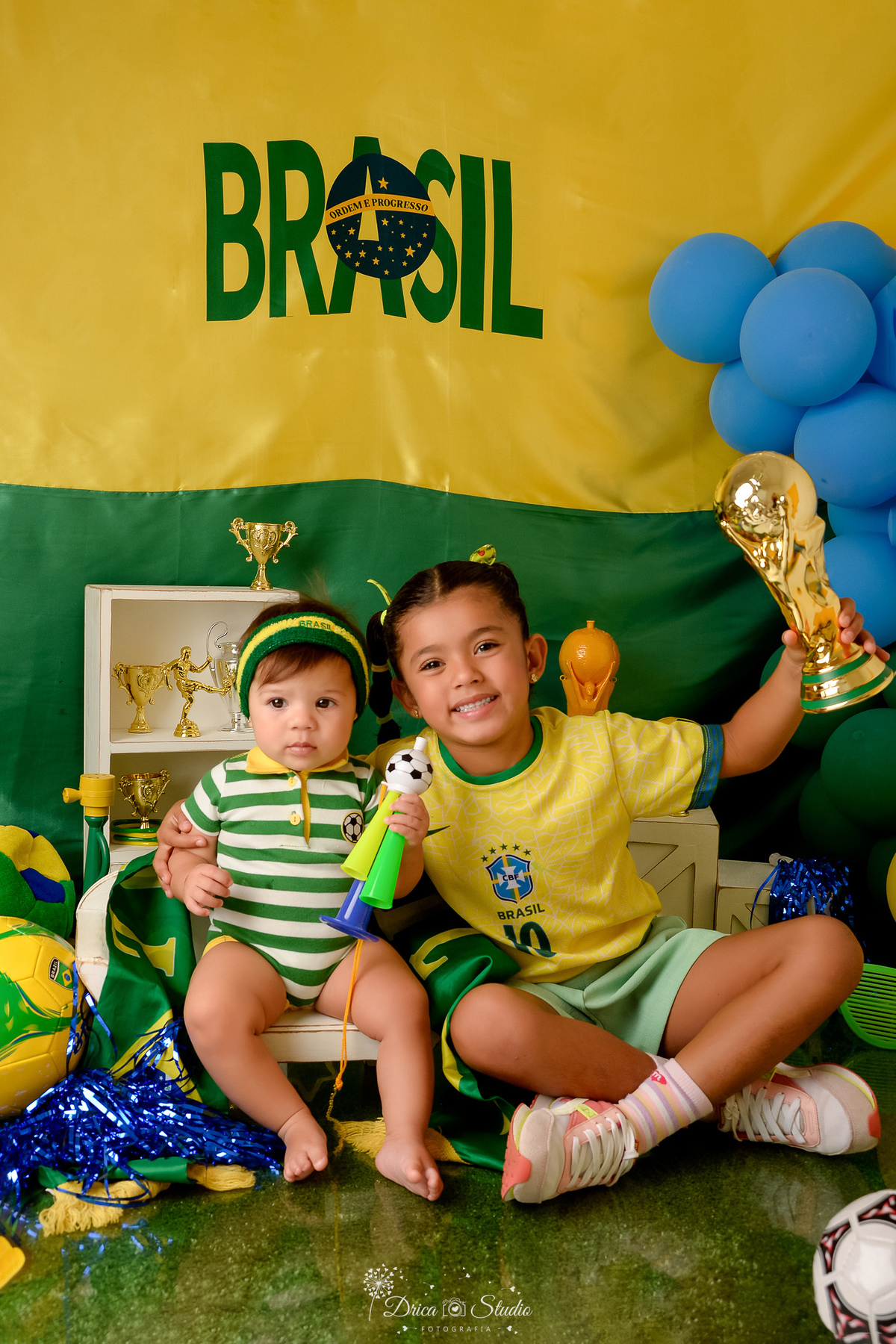 Drica Studio - Copa2026 -Lembrança especial primeira copa - cenário de copa - verde, amarelo e azul - irmãs torcendo juntas - com roupa do brasil e taça da copa do mundo - 