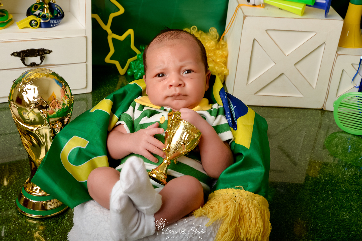 Drica Studio - Copa2026 -Lembrança especial primeira copa - cenário de copa - verde, amarelo e azul - bebê usando bory do brasil - com taça - sentado em um baquinho branco -
