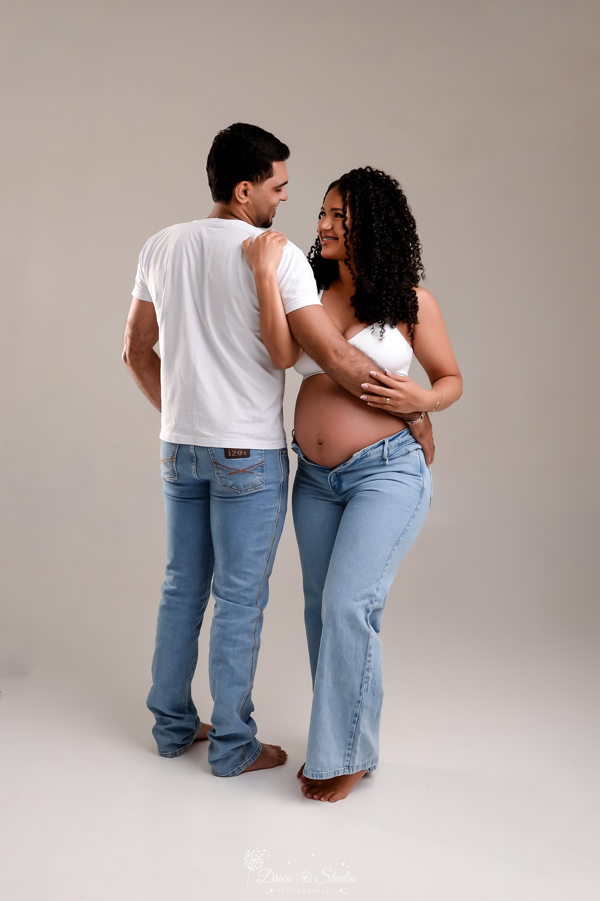 drica studio - ensaio gestante - primeiro filho - fotos em estudio - xinguara - pará - mãe usando top branco com calça jeans - pai usando camisa branca e calça jeans - 