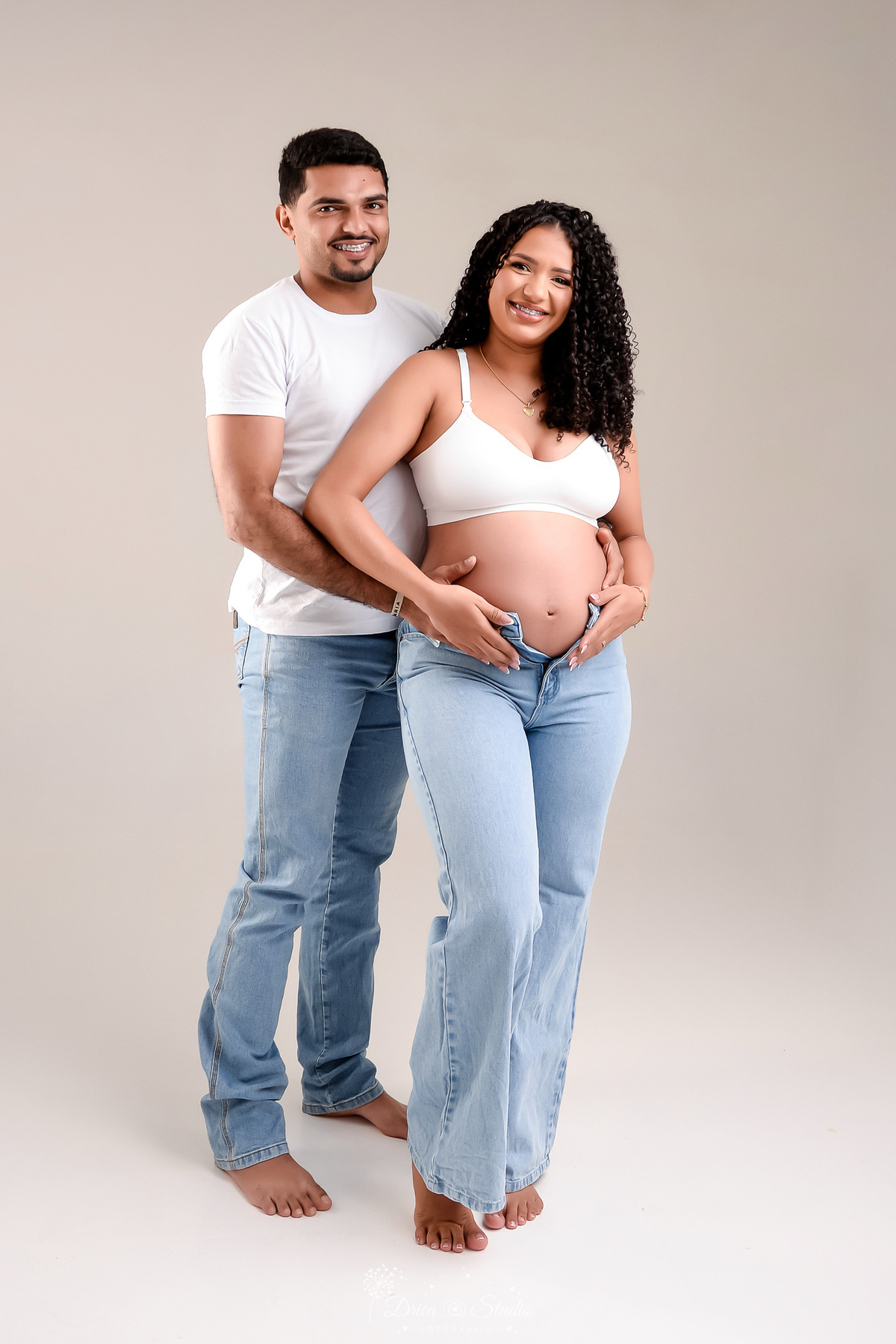drica studio - ensaio gestante - primeiro filho - fotos em estudio - xinguara - pará - mãe usando top branco e calça jeans - pai usando camisa branca e calça jeans 