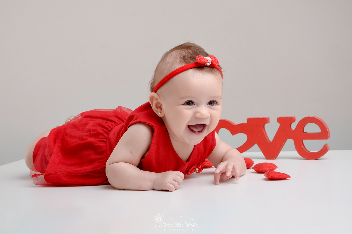 drica studio - acompanhamento mesal - 4 meses - xinguara - pará - bebe usando vertido e laço vermelho - fundo branco - bebe sorrindo 