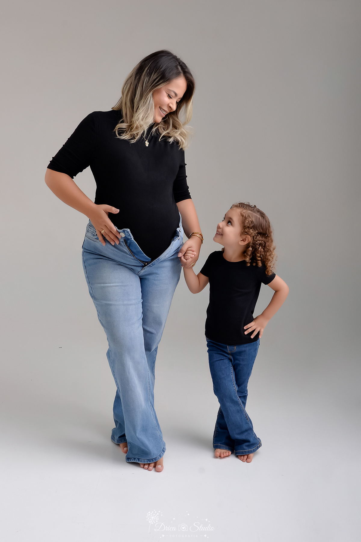 ensaio familia - ensaio gestante - mãe de 2 - irmã mais velha - ensaio em studio - xinguara -pará - mãe e filha - usando calça jeans e camisas pretas - mamãe com a mão na barriga - mãe e filha se olhando 